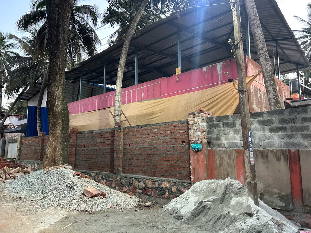 Site photograph before work began: street view of the old structure with a pink parapet and tin roof